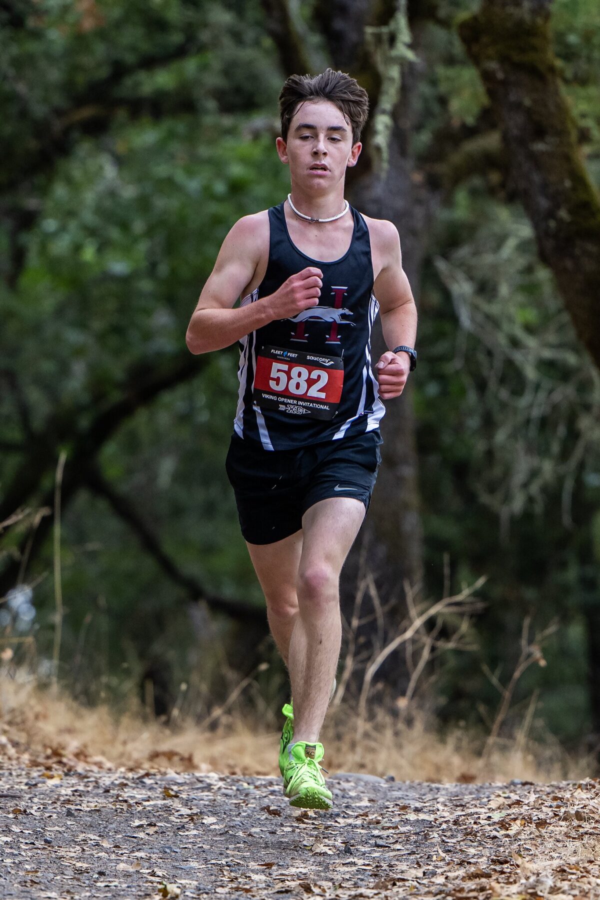 Runner in black athletic gear competing in an outdoor race.