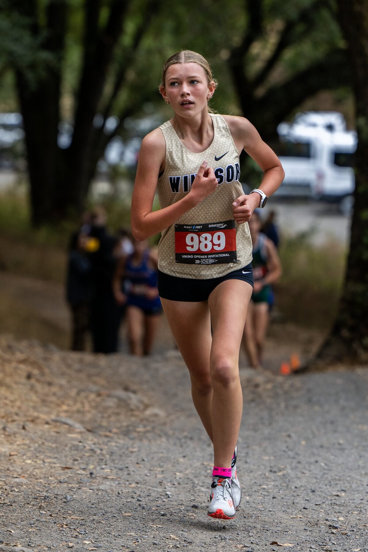 Female athlete running in a cross-country race through a wooded trail.