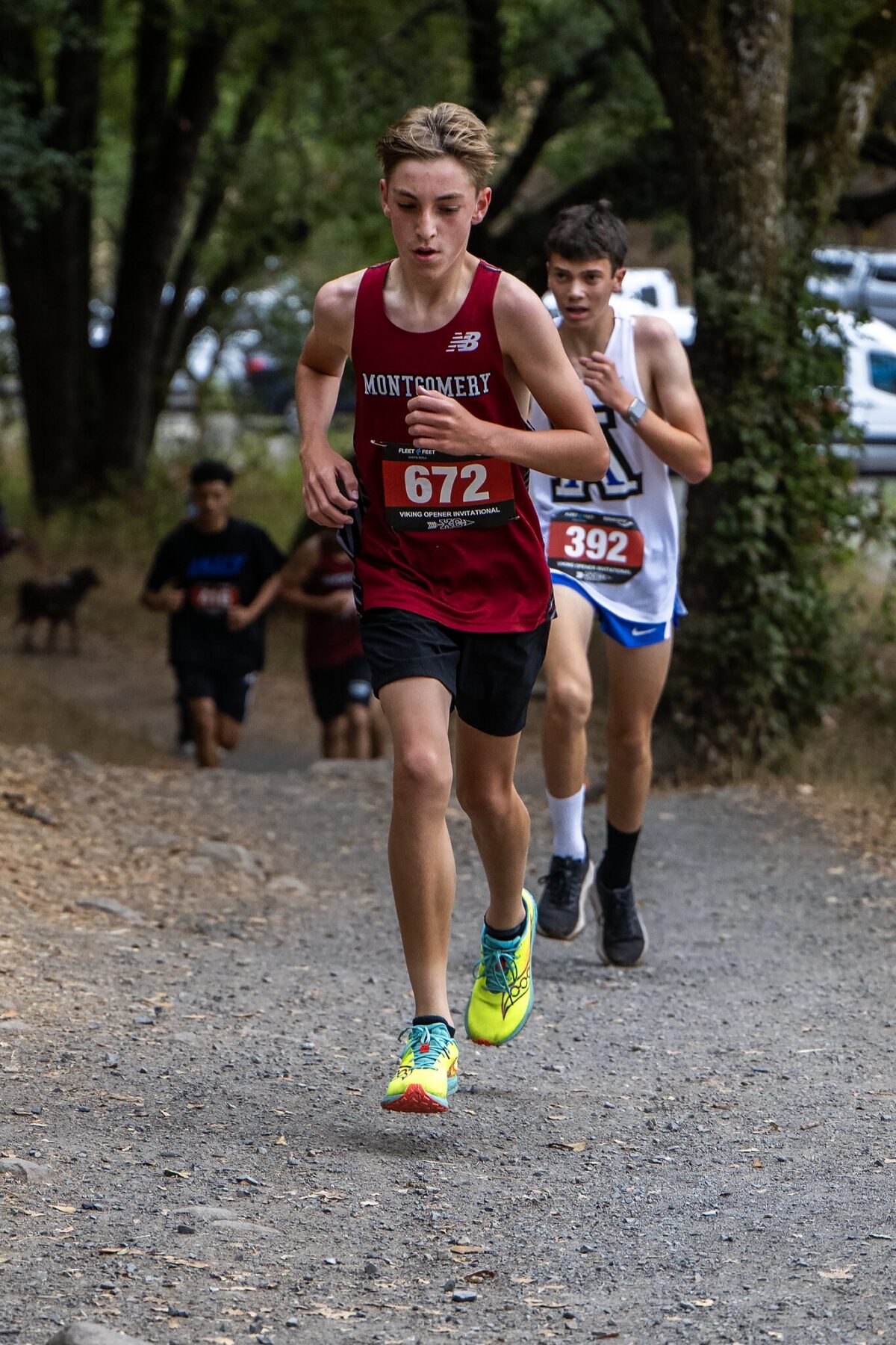 Two runners competing on a forest trail during a race.