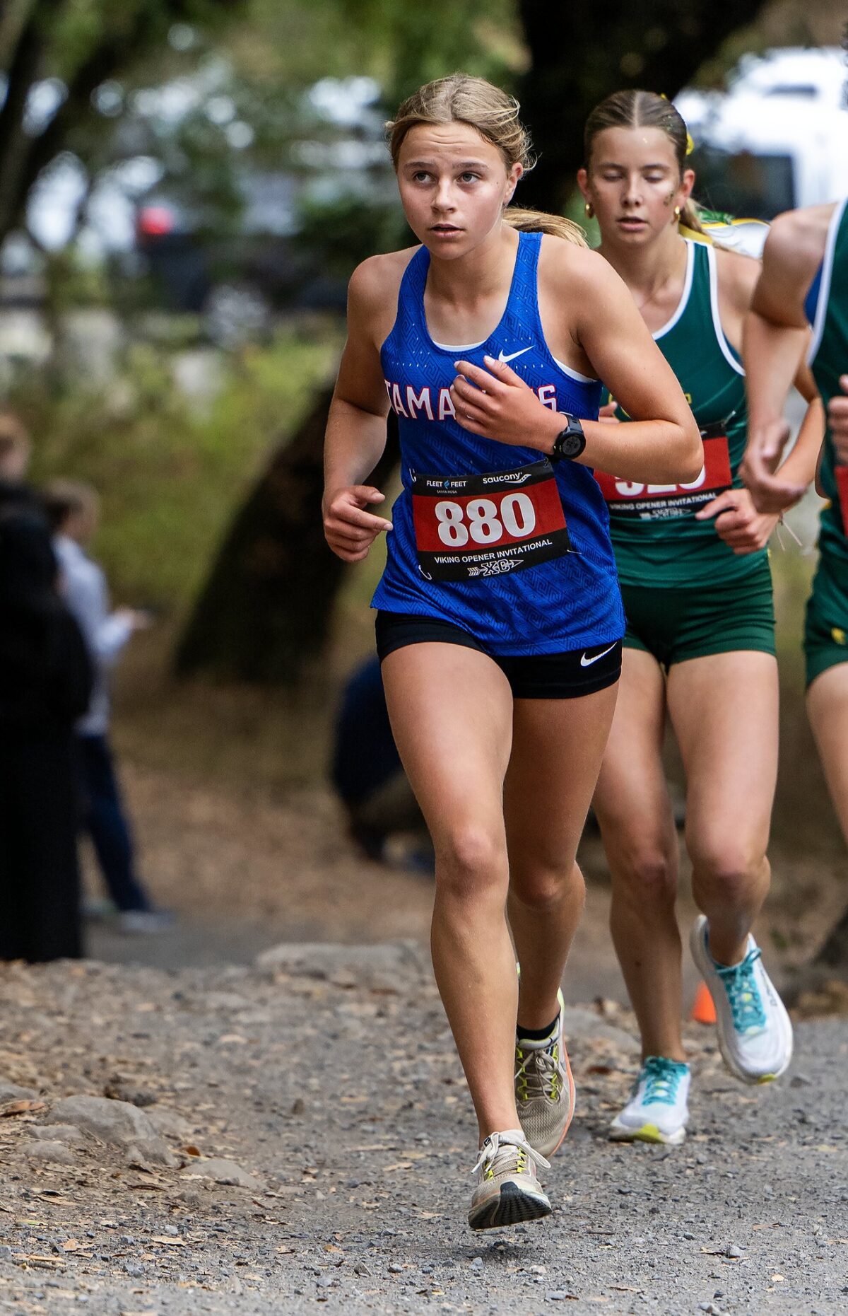 Female runners competing in a cross-country race on a dirt trail.