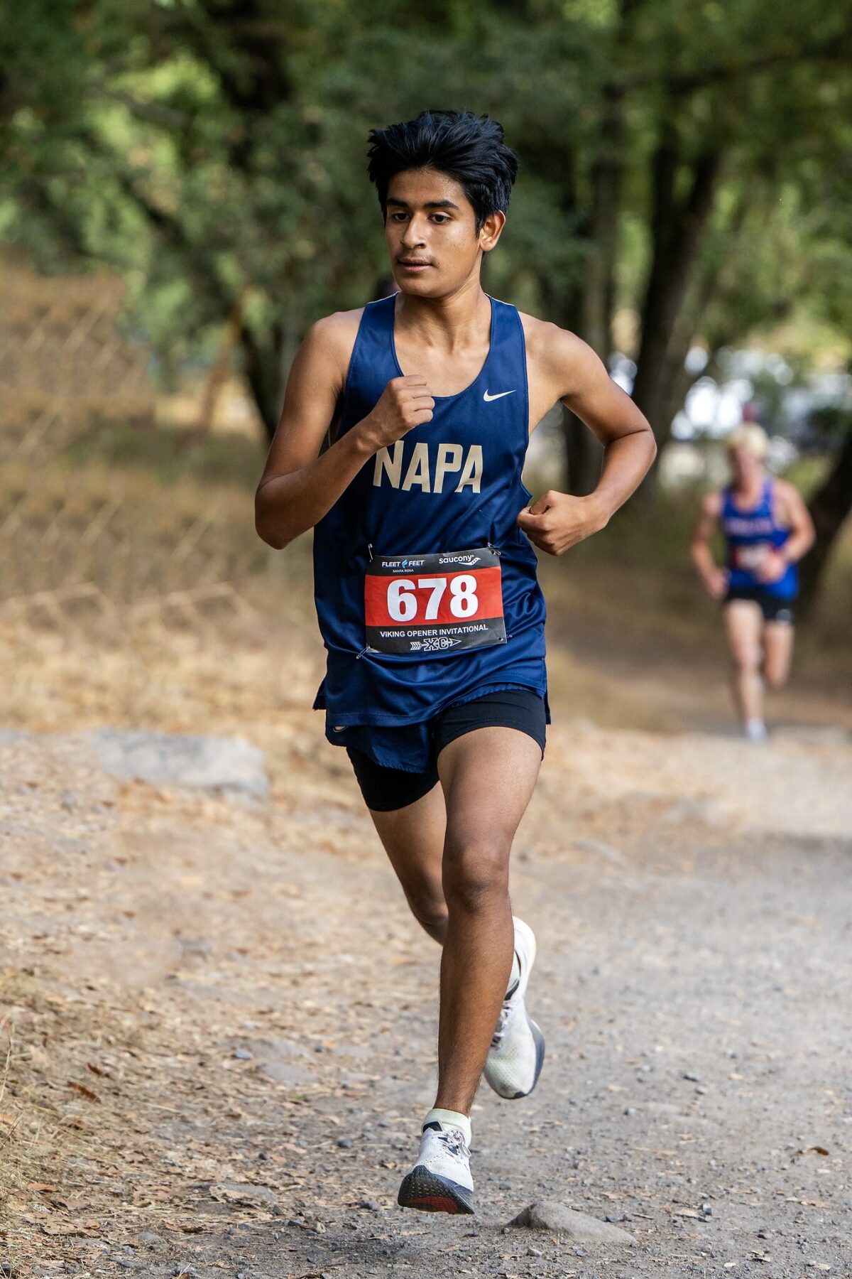 Young male runner in a blue Napa uniform running on a trail race.