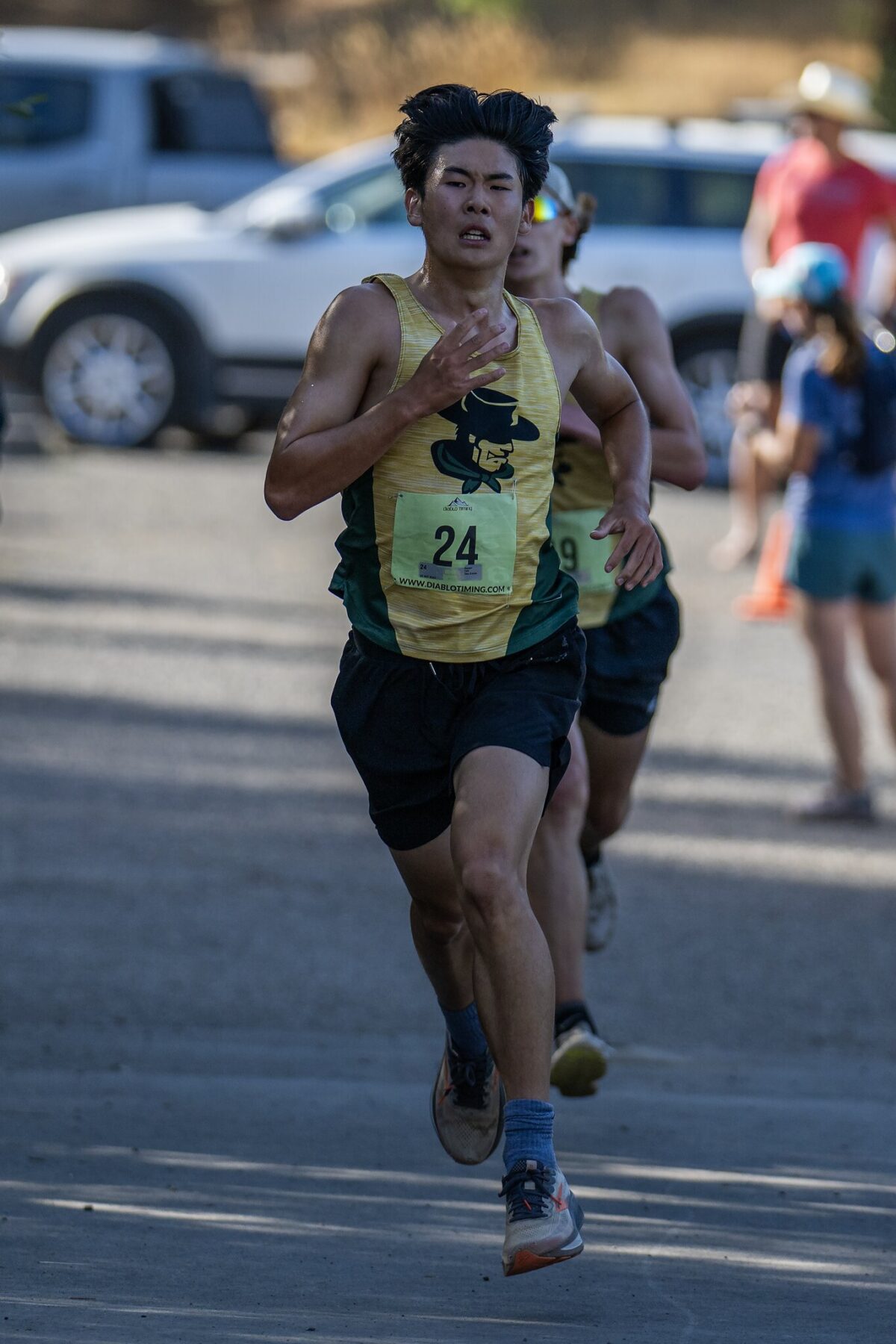 Runner wearing bib 24 races intensely on a road with others behind.