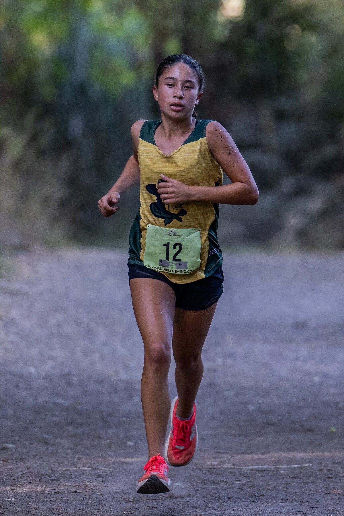 Young female runner in a yellow shirt and black shorts running outdoors.