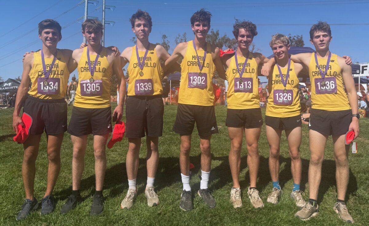 Five young male runners in yellow team uniforms posing with medals outdoors.