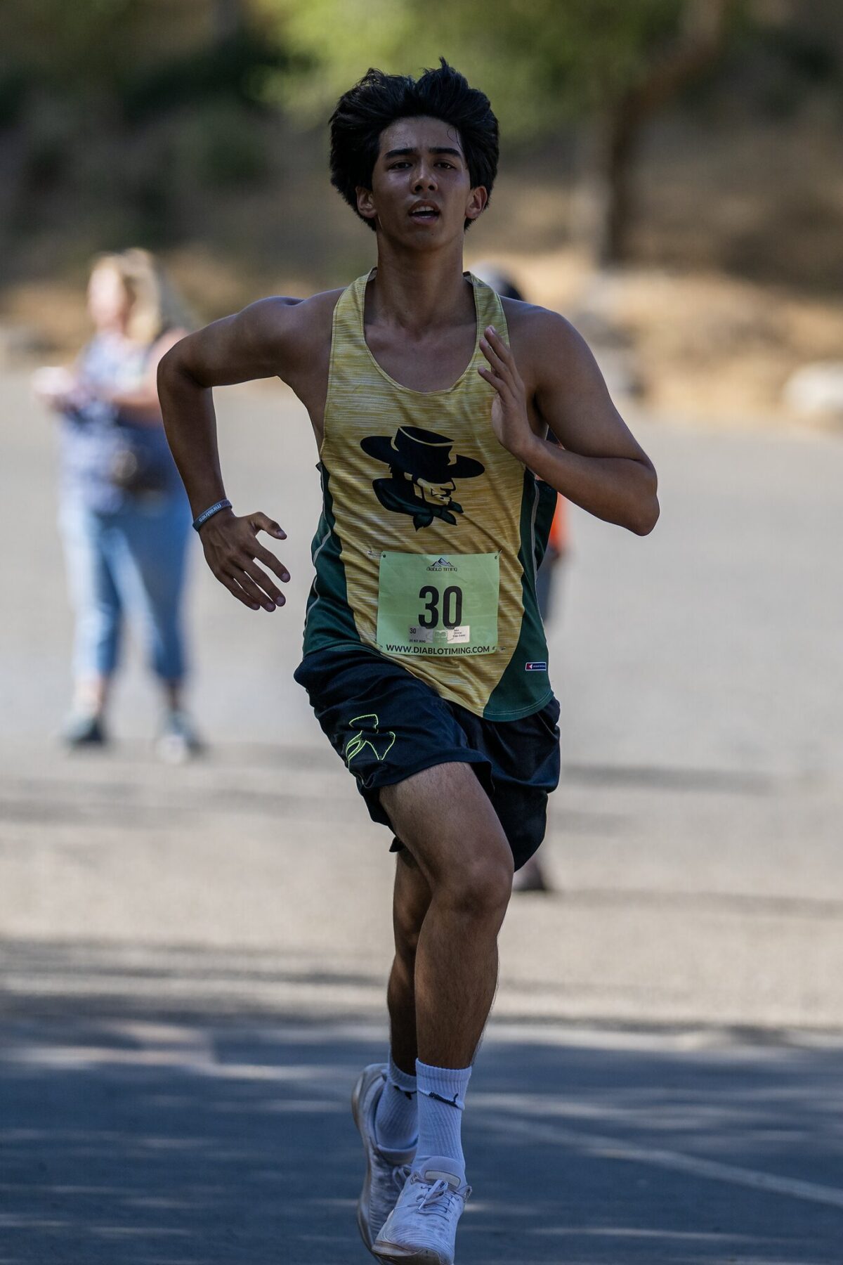 A male runner wearing a yellow tank top and black shorts during a race.
