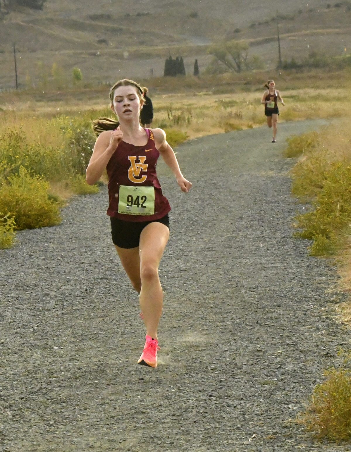 Female runner competing on a gravel trail in a cross-country race.