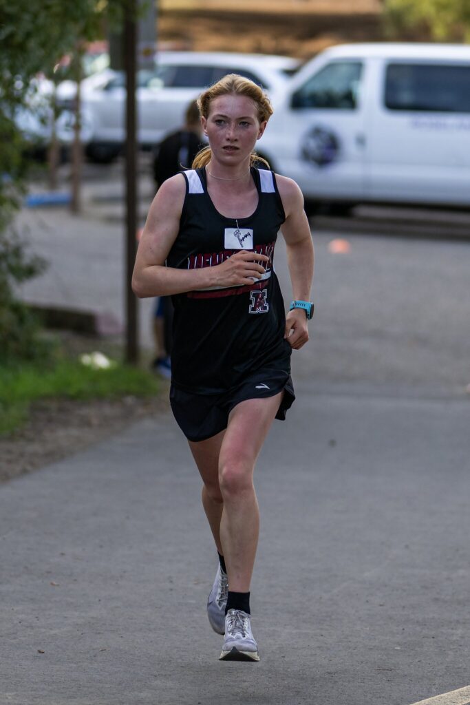 Female runner in black singlet racing outdoors