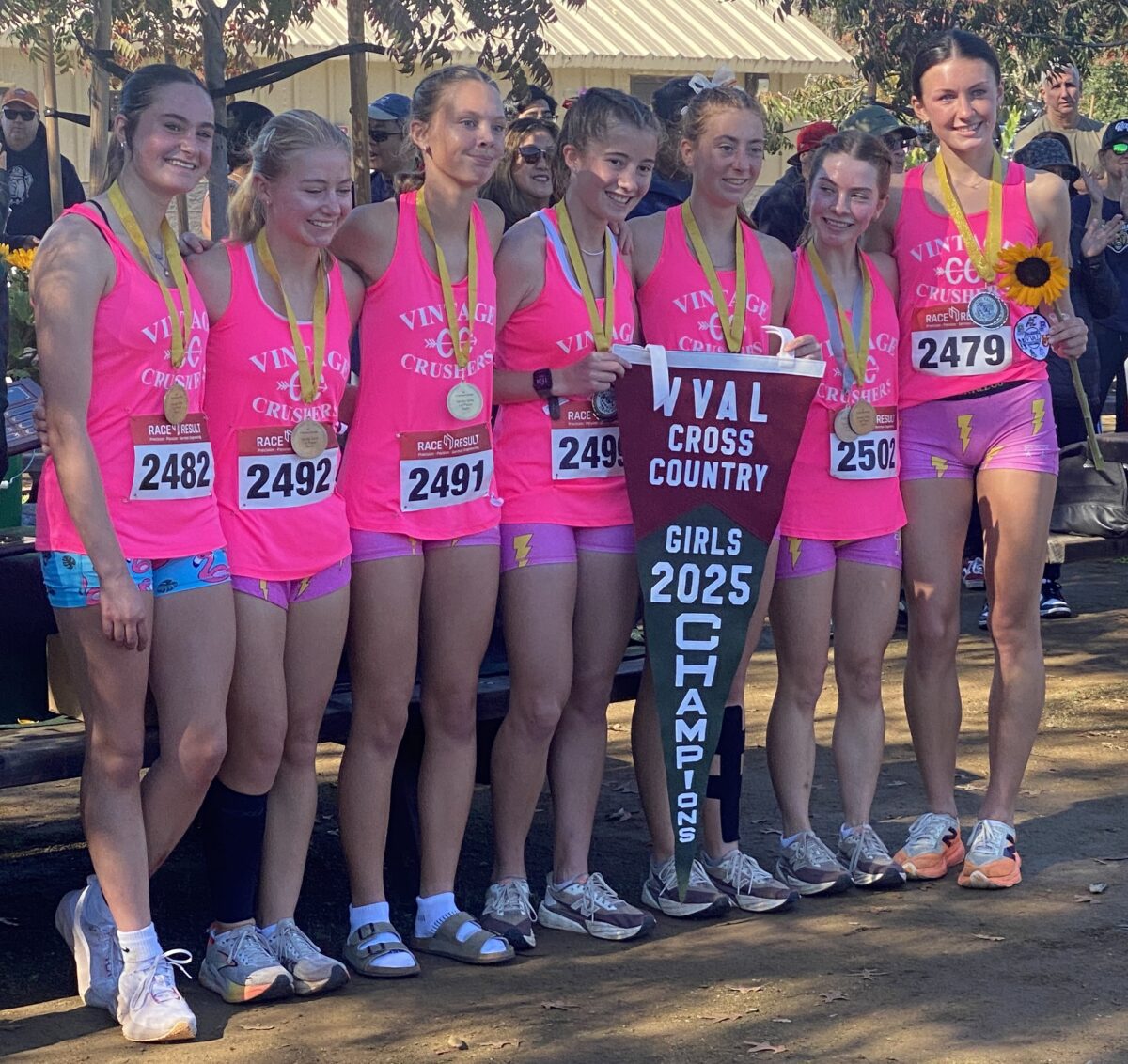 Girls cross country team holding 2025 champions banner