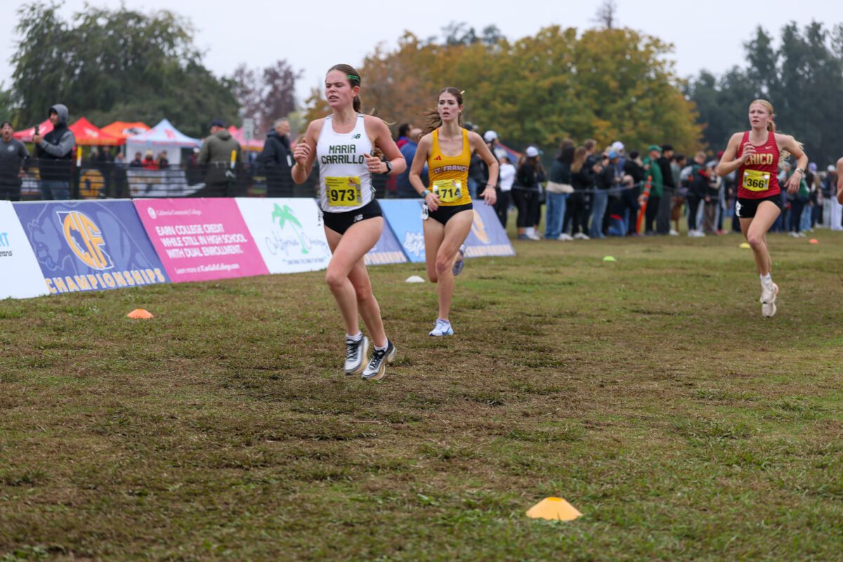 Female cross-country runners racing on grassy course