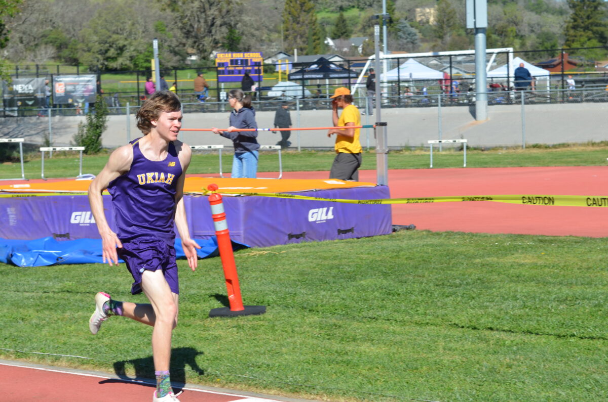 Track athlete in purple passing high jump pit