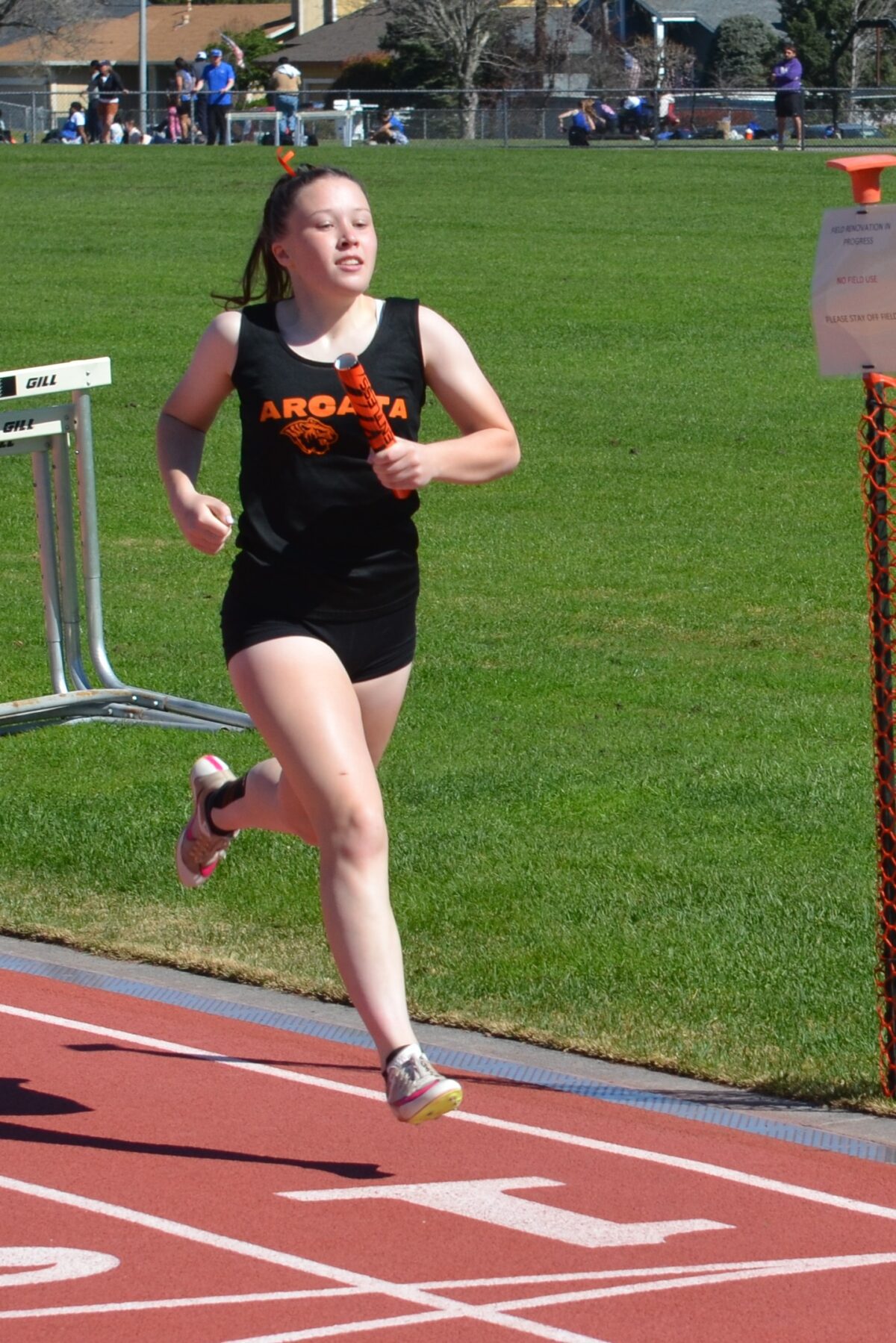 Runner holding relay baton on track
