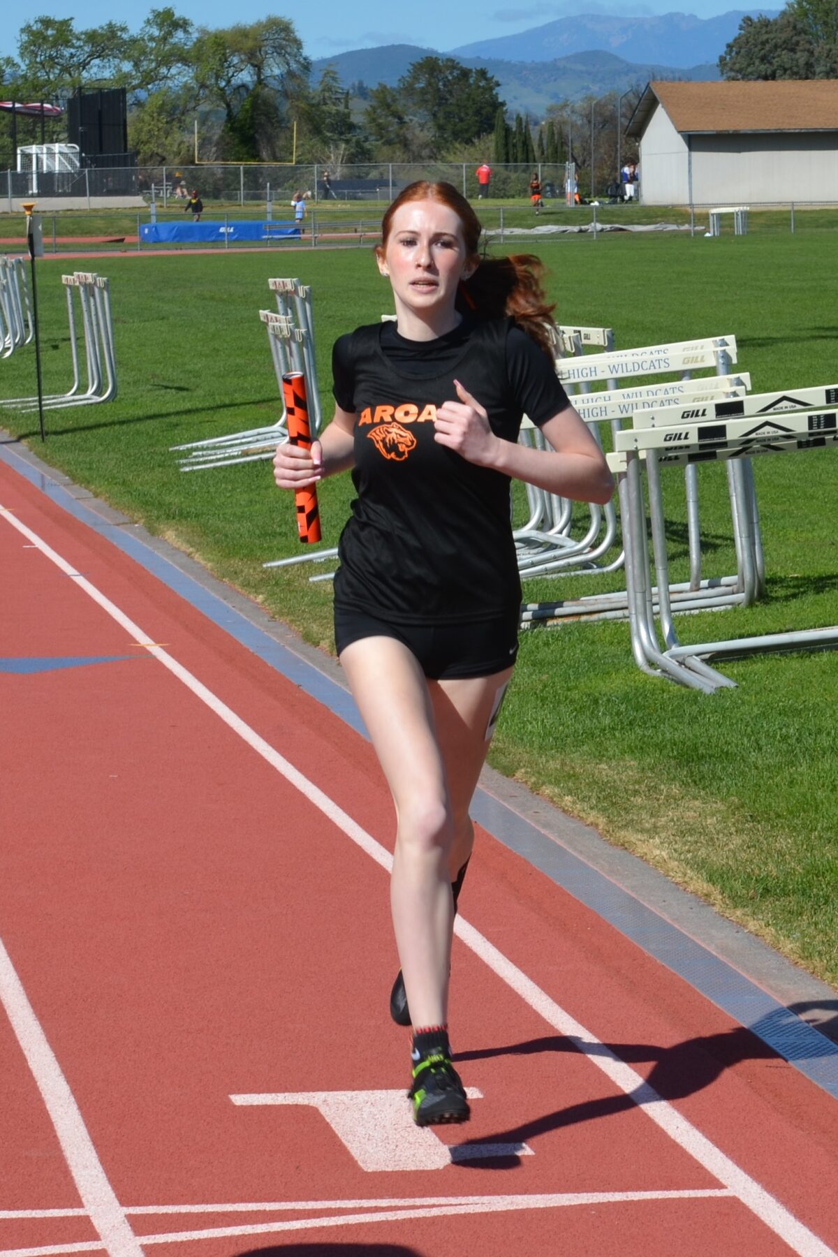 Athlete running on track holding relay baton