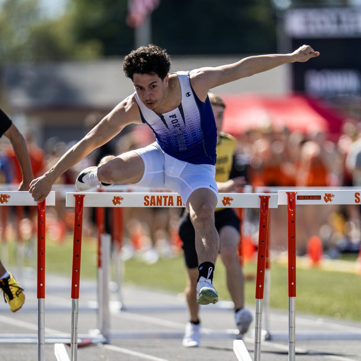 Male athlete hurdling during track meet