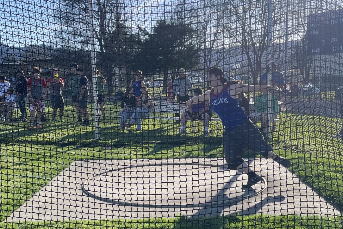 Athlete spinning to release discus behind net