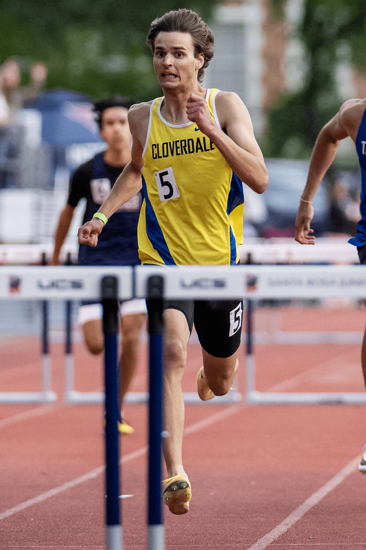 Runner in yellow Cloverdale jersey clearing hurdle