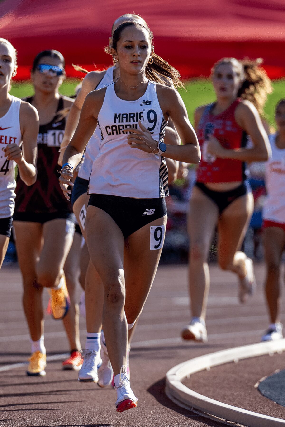 Female runner leading group around track curve