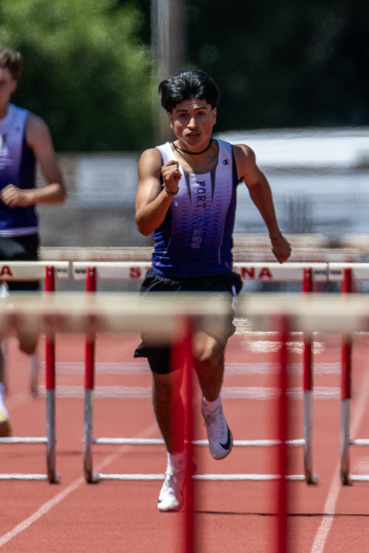 Sprinter hurdling on outdoor red track